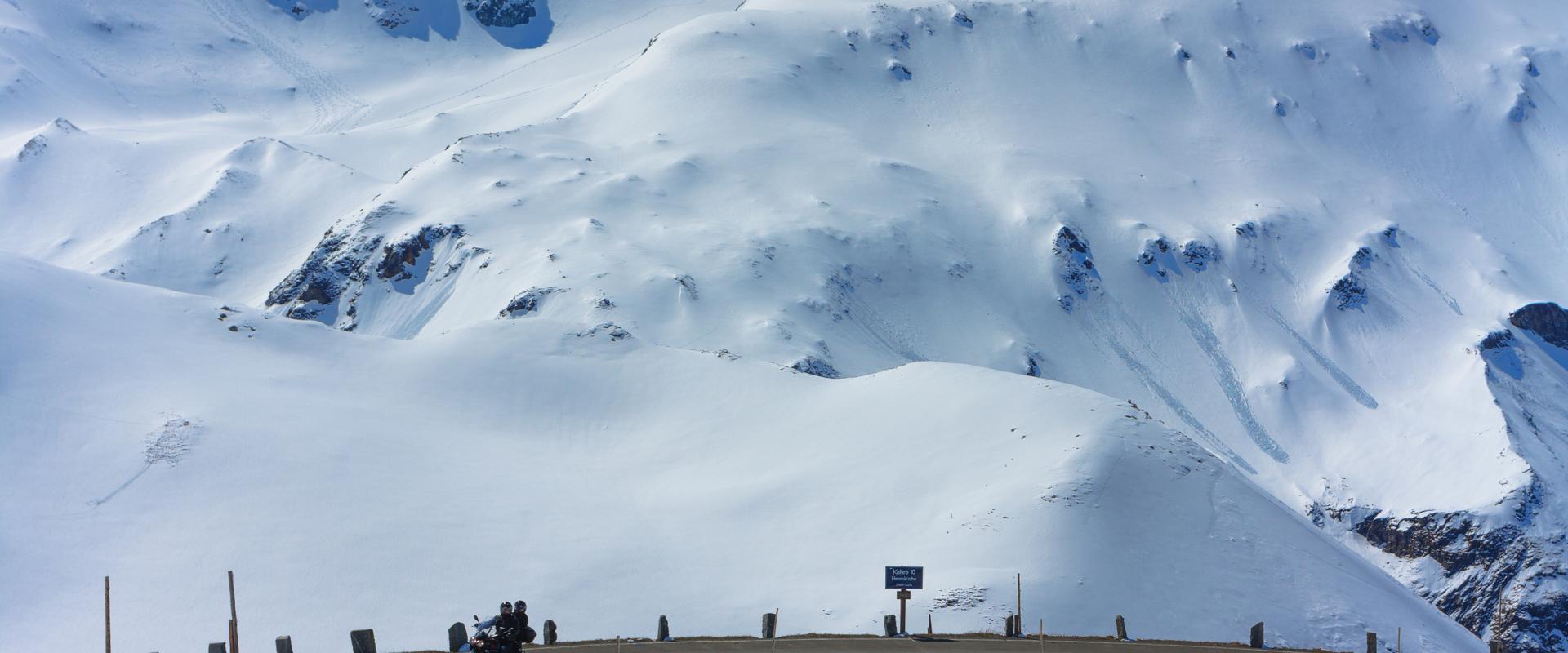 Motorradfahrer in einer Kehre der Grossglockner Hochalpenstraße, mit Blick auf schneebedeckte Berge