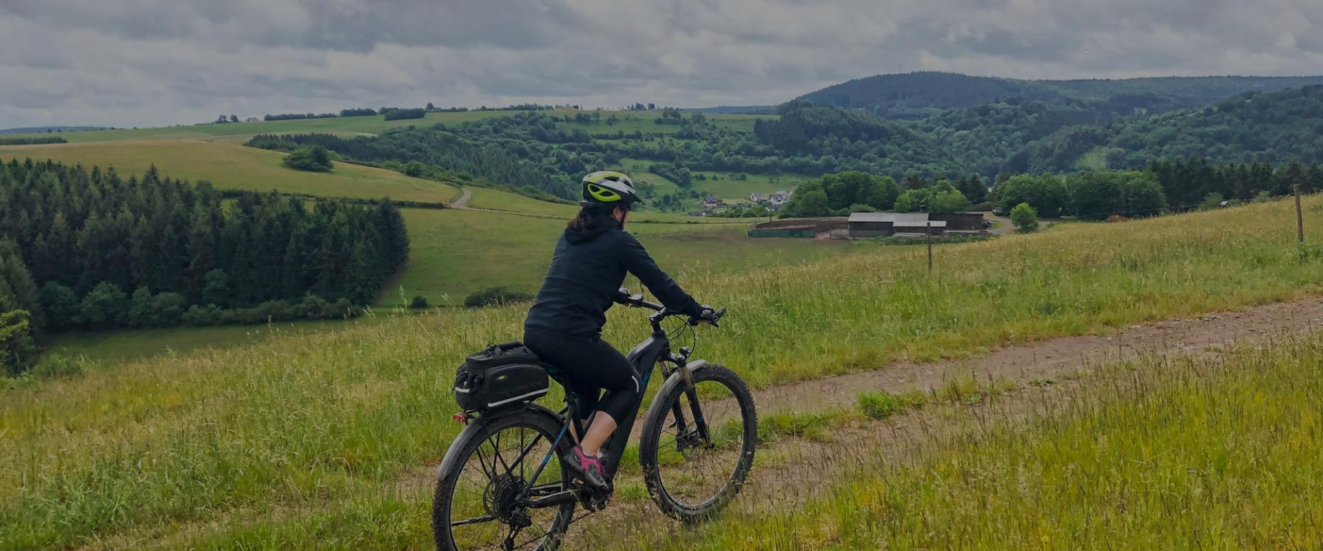 Frau fährt Ebike durch Mittelgebirgslandschaft in Deutschland