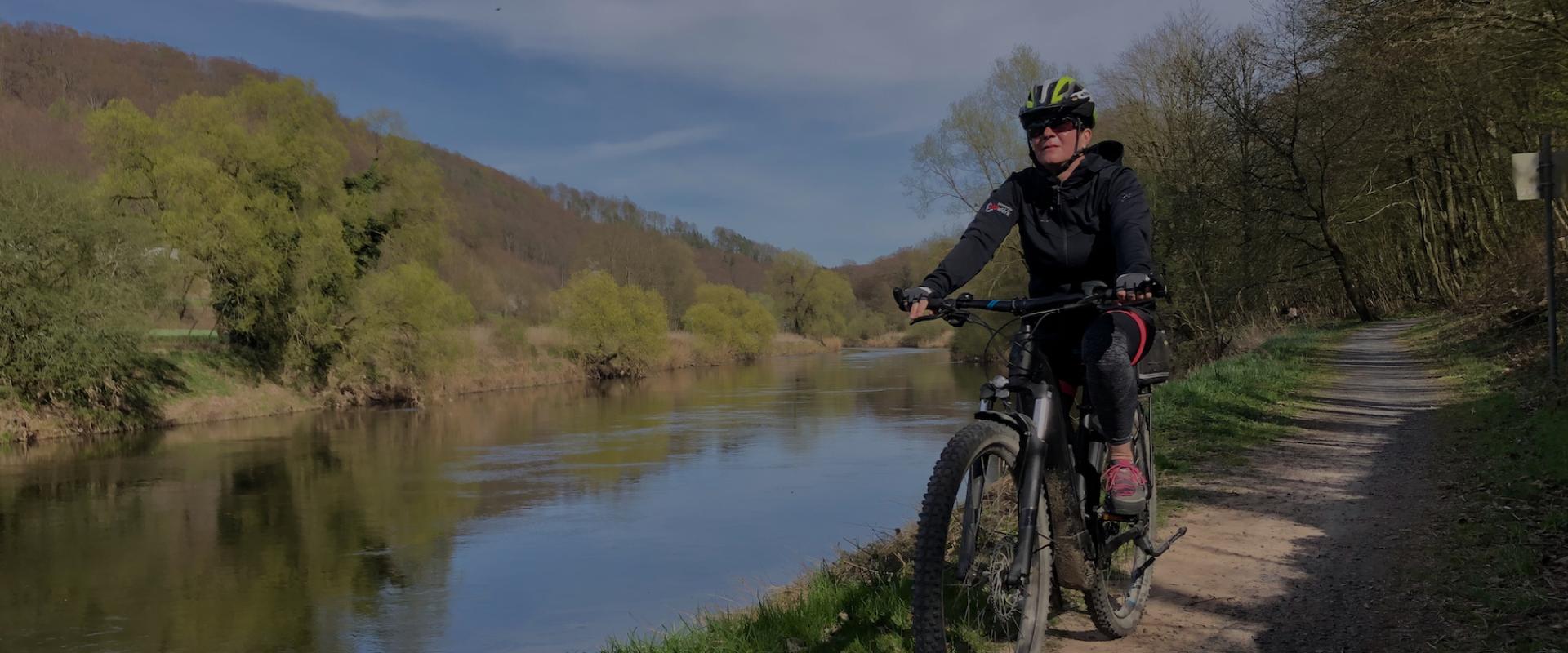 Frau fährt Ebike entlang der Weser im Weserbergland