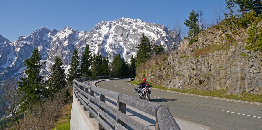 Motorrad auf der Rossfeld Panoramastraße, mit Bäumen und Bergen im Hintergrund