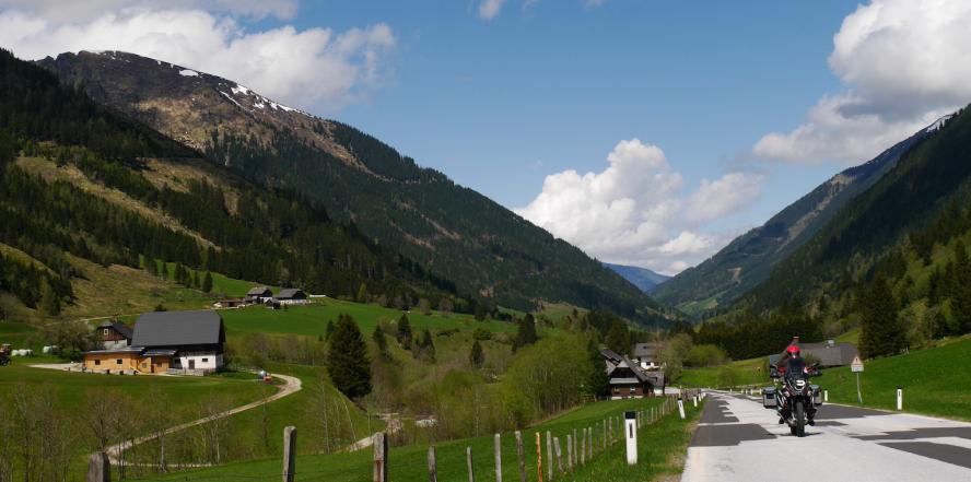 Motorradfahrer auf dem Sölkpass, mit Bergen und Wiesen im Hintergrund