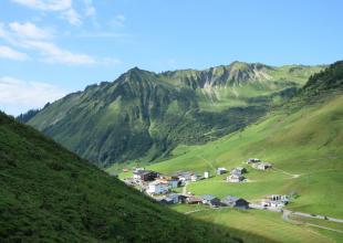Ausblick des Faschinajochs, auf Dorf, Wiesen und Berge 