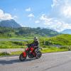 Motorradfahrer auf dem Hochtannbergpass, mit See, grünen Wiesen und Bergen im Hintergrund